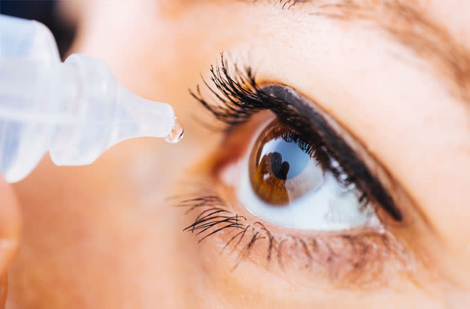 man using eye drops