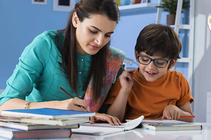 A young boy wearing spectacles gets help with his homework